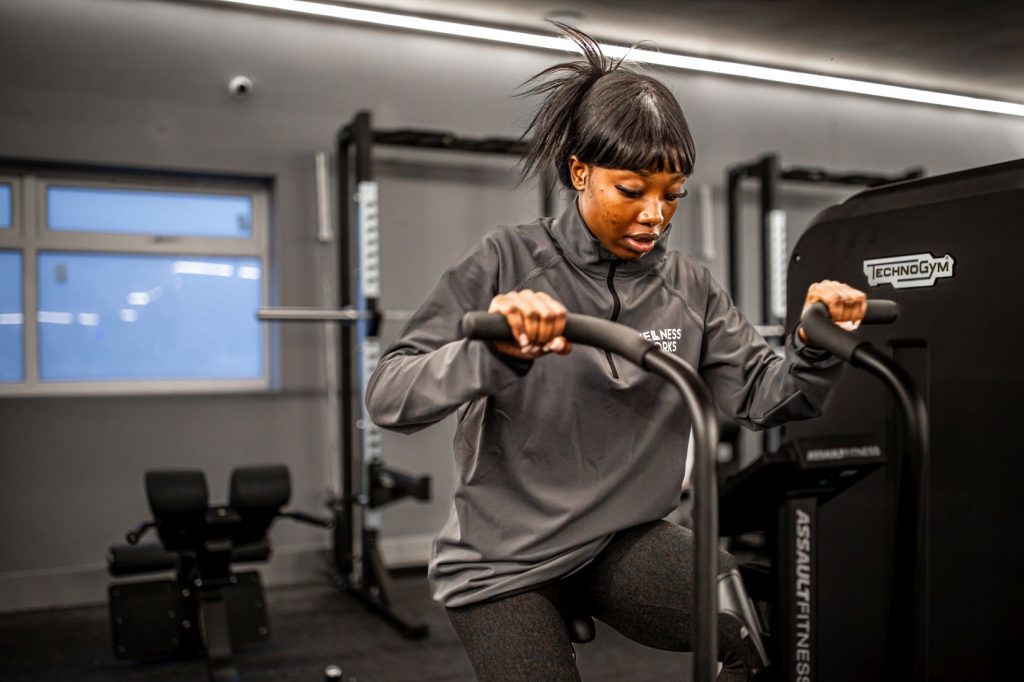 Woman working out on an elliptical trainer, moving both her arms and legs.